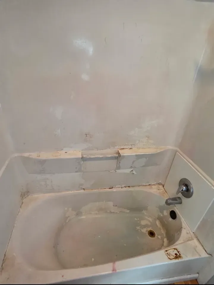 Worn damaged bathtub and surround before reglazing